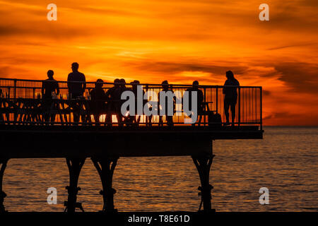 Aberystwyth Wales UK, Sunday 12 May 2019  UK Weather: People enjoying a drink on the pier are silhouetted by the setting sun  on a glorious evening  in Aberystwyth on the Cardigan Bay coast, West Wales, at the end of a day of unbroken clear blue skies and warm spring sunshine  photo credit Keith Morris / Alamy Live News Stock Photo