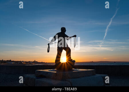 Newlyn, Cornwall, UK. 13th May 2019. A fresh breeze and another glorious sunrise with Tom Leapers memorial to Newlyn Fisherman statue silhouetted by the rising Sun. Credit Simon Maycock / Alamy Live News. Stock Photo