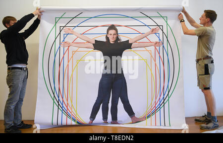 Hessen, Germany. 13 May 2019, 13 May 2019, Hessen, Gießen: A large print by the Leonardo man, a 'Vitruvian proportional study', is unfurled during the construction of a special exhibition at the interactive museum 'Mathematikum'. Visitors can go in an exhibition to touch on the traces of Leonardo da Vinci. At around 20 stations and exhibits, they can try out whether the machines drawn by the Renaissance artist really work and what lies behind his ideas. The show 'Leonardo in the Mathematikum' runs from 18 May 2019 to 29 March 2020. Credit: dpa picture alliance/Alamy Live News Stock Photo