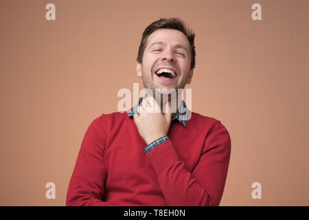 European young man in red sweater laughing on funny joke Stock Photo