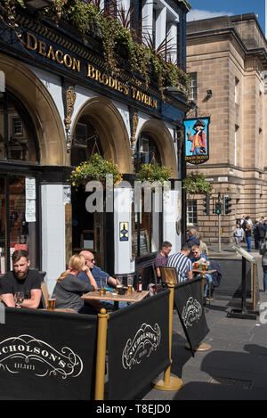 Customers enjoying a drink in the sunshine outside Deacon Brodie's Tavern in the Lawnmarket, Edinburgh, Scotland, UK. Stock Photo