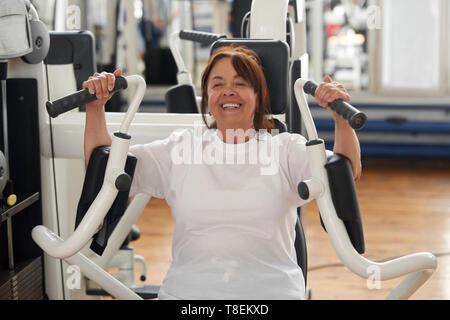 Woman using a chest press machine in a gym Stock Photo - Alamy