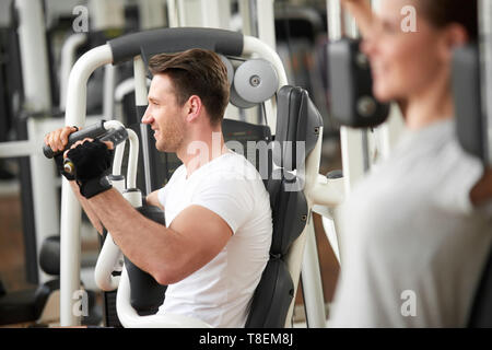 Young handsome man working out in fitness center. Handsome caucasian male doing chest exercises. Muscular body through hard uwork. Stock Photo