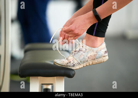 Close up woman tying sport shoes. Female hands tying shoelaces at gym, side view. Ready for training. Stock Photo