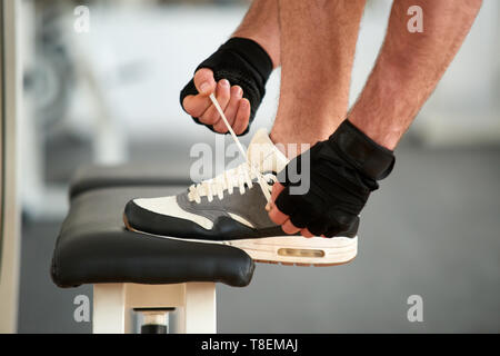 Man tying running shoes in gym. Close up shot of man lacing sneakers indoors. Ready for workout. Stock Photo