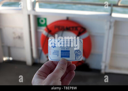 Holding a one-way ferry ticket with life ring in background Stock Photo