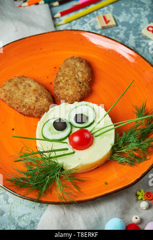 Kids menu, cutlets with mashed potatoes in the form of a hare's head on an orange plate on a gray background Stock Photo