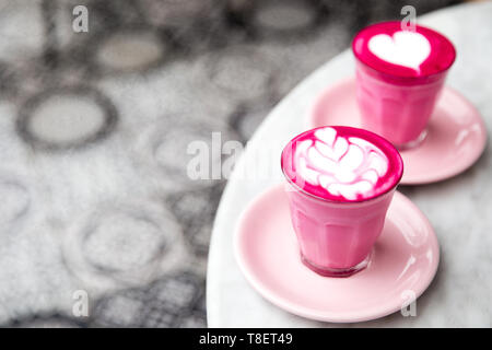 Two glasses of pink beetroot latte with beautiful latte art on marble table background. Trendy healthy drink. Stock Photo