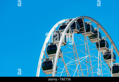 Closeup modern Ferris wheel against blue sky and white clouds. Ferris wheel at funfair for entertainment and recreation on holiday. Modern Stock Photo