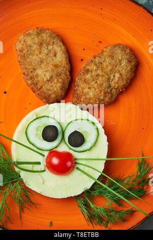 Kids menu, cutlets with mashed potatoes in the form of a hare's head on an orange plate on a gray background Stock Photo