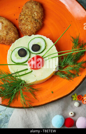 Kids menu, cutlets with mashed potatoes in the form of a hare's head on an orange plate on a gray background Stock Photo