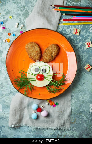Kids menu, cutlets with mashed potatoes in the form of a hare's head on an orange plate on a gray background Stock Photo