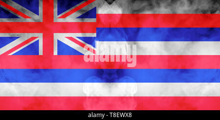 The national flag of the US state Hawaii in against a gray smoke on the day of independence in different colors of blue red and yellow. Political and  Stock Photo