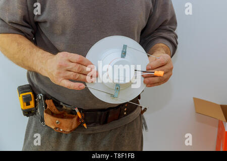 Man is installing electrical light in the ceiling replacing repair works in the flat. Stock Photo