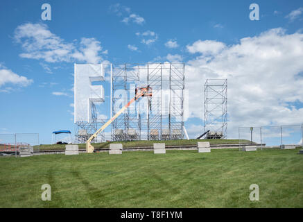 Construction workers installing large sign in an empty field. Stock Photo