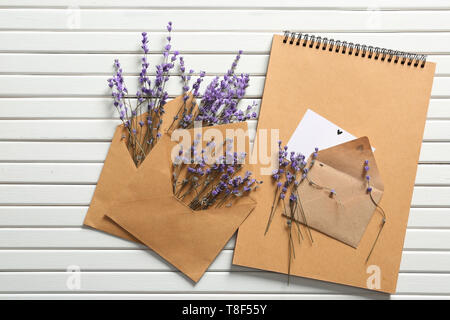 Mail envelopes with lavender flowers and notebook on white wooden background Stock Photo