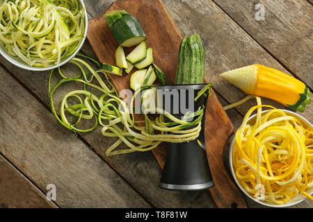 Fresh zucchini spaghetti with spiral grater on wooden table Stock Photo