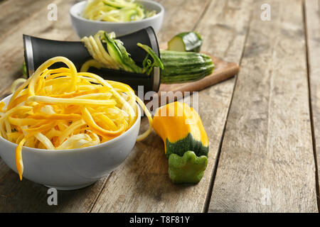 Fresh zucchini spaghetti with spiral grater on wooden table Stock Photo