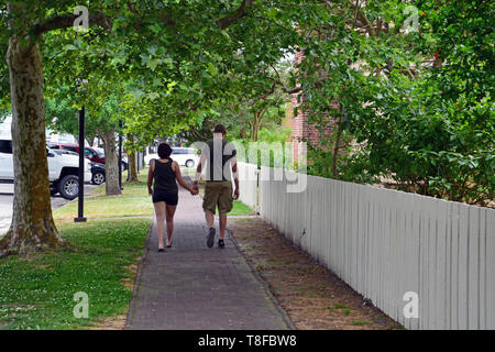 A couple walks down a tree shaded sidewalk near downtown in the picturesque small town of Edenton North Carolina. Stock Photo