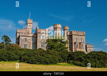 Lews Castle on blue sky in Stornoway, United Kingdom. Castle with green trees on natural landscape. Victorian style architecture and design. Landmark and attraction. Summer vacation and wanderlust. Stock Photo