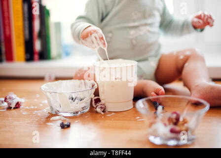 A midsection of small messy toddler boy sitting on kitchen counter at home, eating. Stock Photo