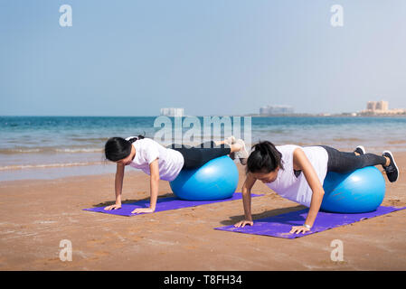 Women exercising with pilates yoga ball on the beach
