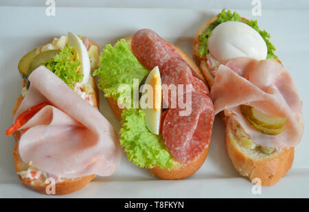 Traditional czech party food snack served on special occasions - three open sandwiches ('chlebicky') with various toppings: ham, salami, sliced smoked Stock Photo