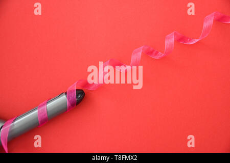 Curling iron isolated on red background. Stock Photo
