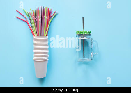 Set of disposable white cups weekly use and counterweight reusable mason gar for drinks daily use on blue background. Zero waste. Plastic free. Stock Photo