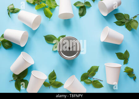 Border of white disposable cup and green leaves on blue background. Save the planet. Zero waste. Top view Stock Photo