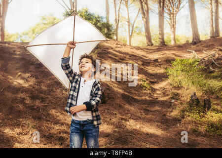 Cute boy flying a kite. Child playing with a handmade kite in forest. Stock Photo