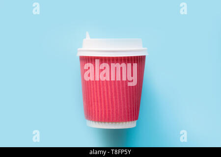 Disposable paper red cup with a white plastic lid for hot coffee or tea on blue. Flat lay, top view. Concept zero waste. Stock Photo