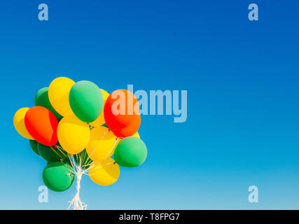 Colourful helium balloons against a blue sky background with copy space Stock Photo