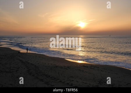 A lone fisherman at Playa Rota beach, as the sun sets, Rota, Andalucía, Spain. Stock Photo
