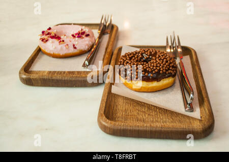Delicicous sweet donuts on wooden plates on a table in a cafe. Stock Photo