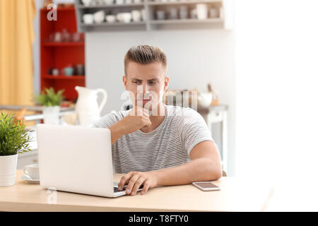 Emotional freelancer working on laptop in kitchen Stock Photo
