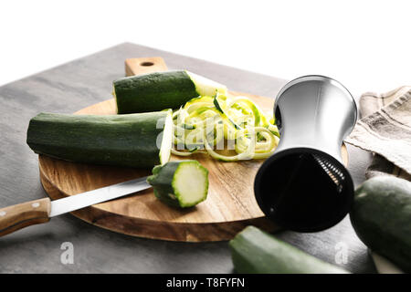 Fresh zucchini spaghetti with  spiral grater on wooden table Stock Photo