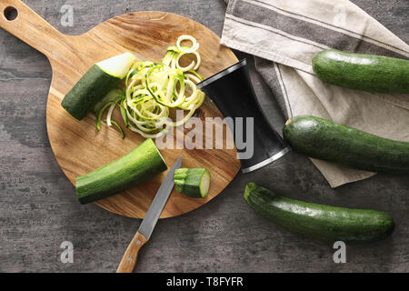 Fresh zucchini spaghetti with  spiral grater on wooden table Stock Photo