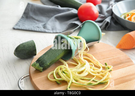 Fresh zucchini spaghetti with spiral grater on wooden board Stock Photo
