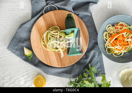 Fresh zucchini spaghetti with spiral grater on light table Stock Photo