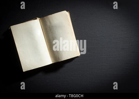 Open old book on black matte surface Stock Photo