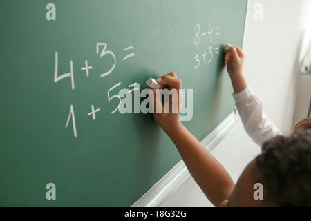 Schoolchildren writing on chalkboard in classroom during math lesson Stock Photo