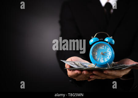 Businessman holding money and clock. time is money investment, success and profitable business concepts. Stock Photo