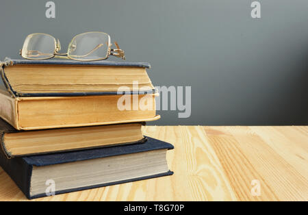Retro books and old eyeglasses on wooden table. Stock Photo