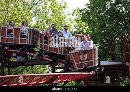 Moscow, Russia - May 2019: People ride on a roller coaster in a amusement park. Happy parents with children have fun in Sokolniki park, family leisure Stock Photo