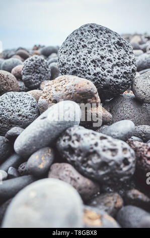 Close up picture of a volcanic rock on a beach, selective focus, color toning applied. Stock Photo