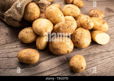 New potatoes on wooden background. Solanum tuberosum Stock Photo