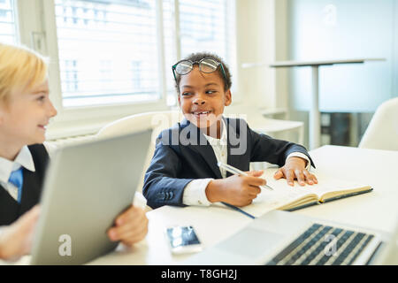 Two children as a multicultural business team work together in the office Stock Photo