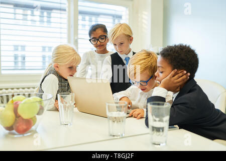 Kids group as a software developer team working together on laptop computer in the office Stock Photo
