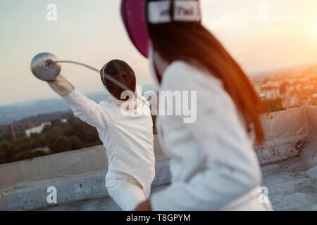 Two fencing athletes people fight on rooftop outdoors Stock Photo